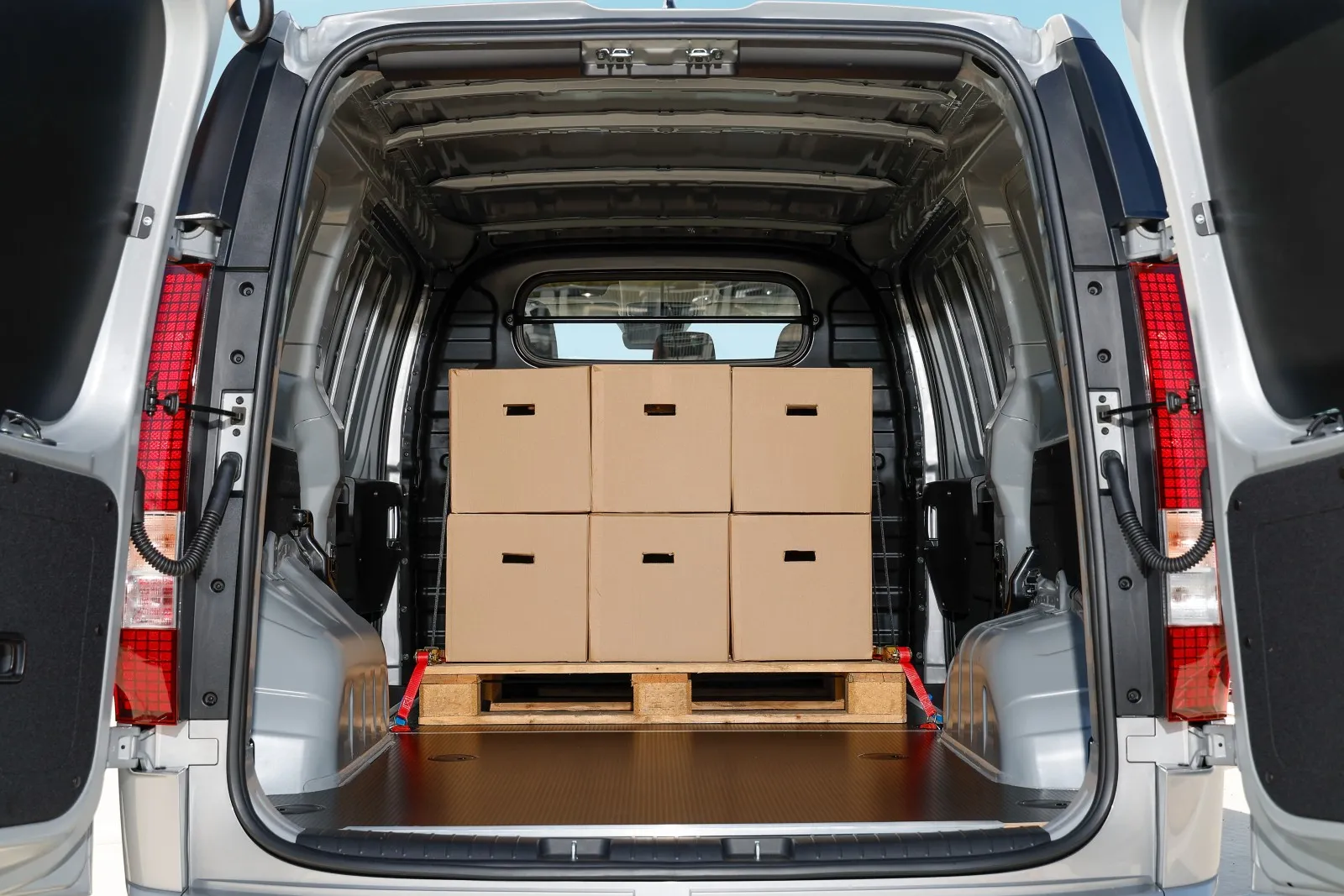 Zona de carga de la Hyundai STARIA Cargo eléctrica con el portón abierto y un palé con cajas