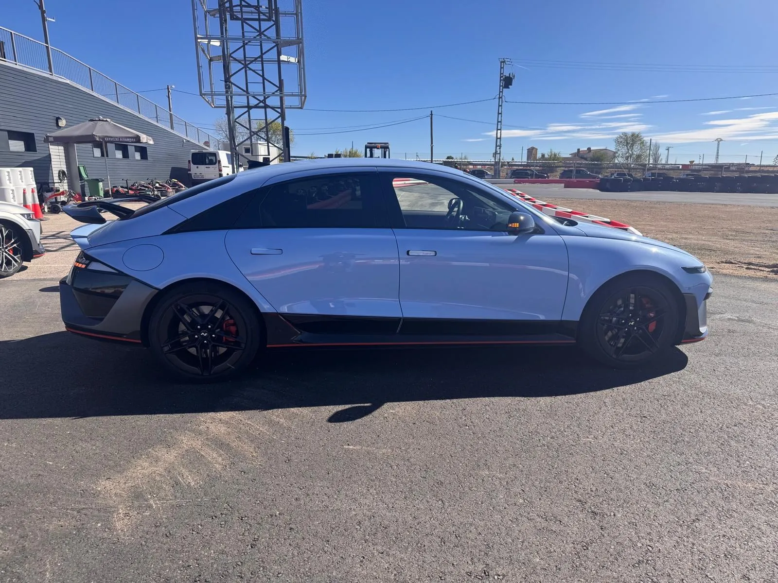 Perfil lateral del Hyundai IONIQ 6 N azul con techo en arco, faldones negros con filo rojo y llantas negras de 20 pulgadas