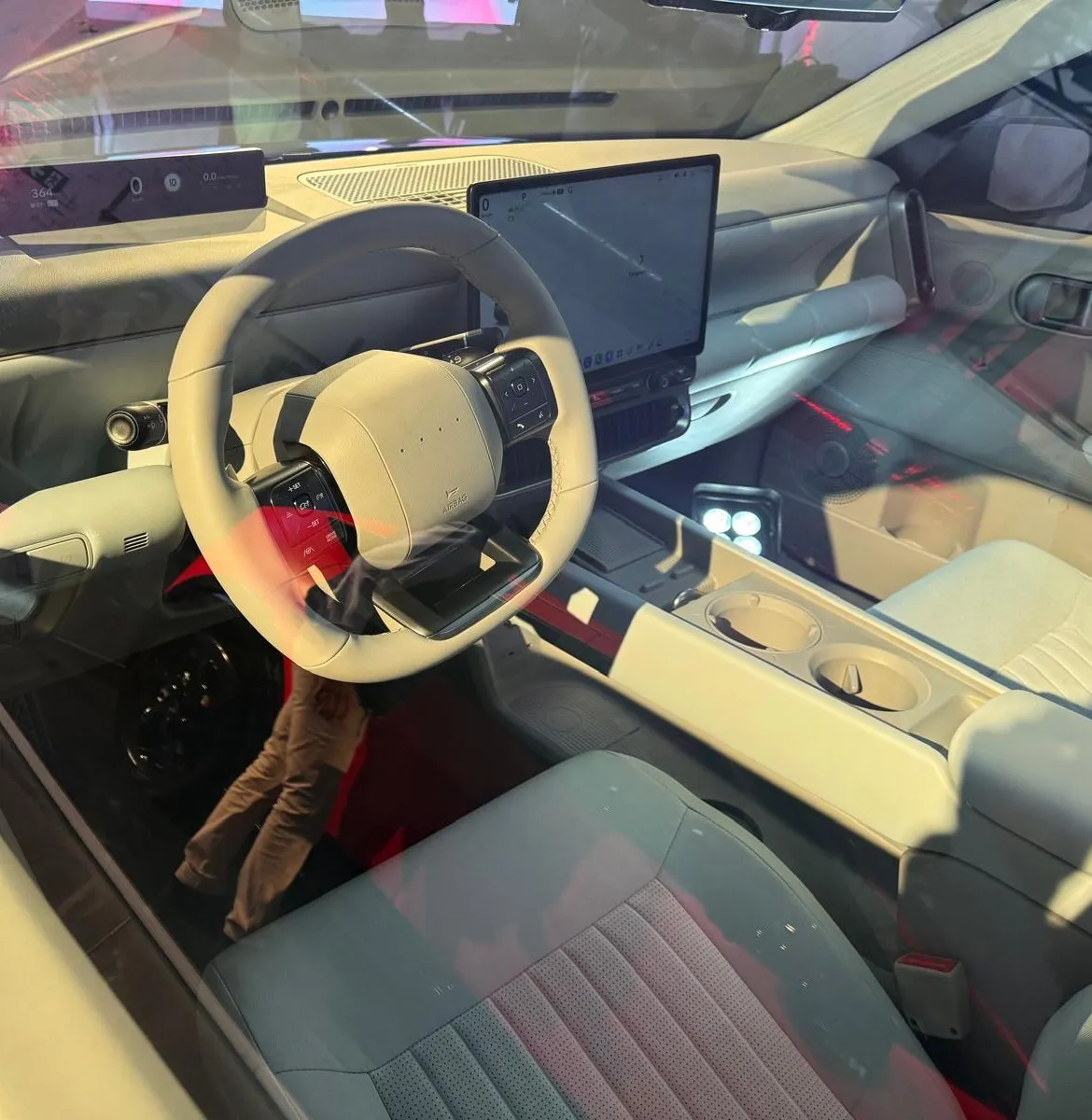 Interior del Hyundai IONIQ 3 en tonos claros con volante achatado, cuadro digital alto y pantalla central Pleos Connect