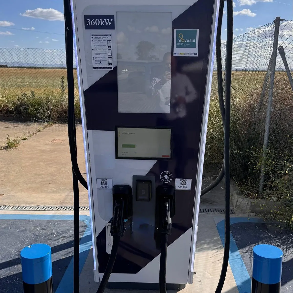 Cargador rápido de 360 kW con dos mangueras, lector de tarjetas, códigos QR en cada toma y pegatina con las instrucciones de la app