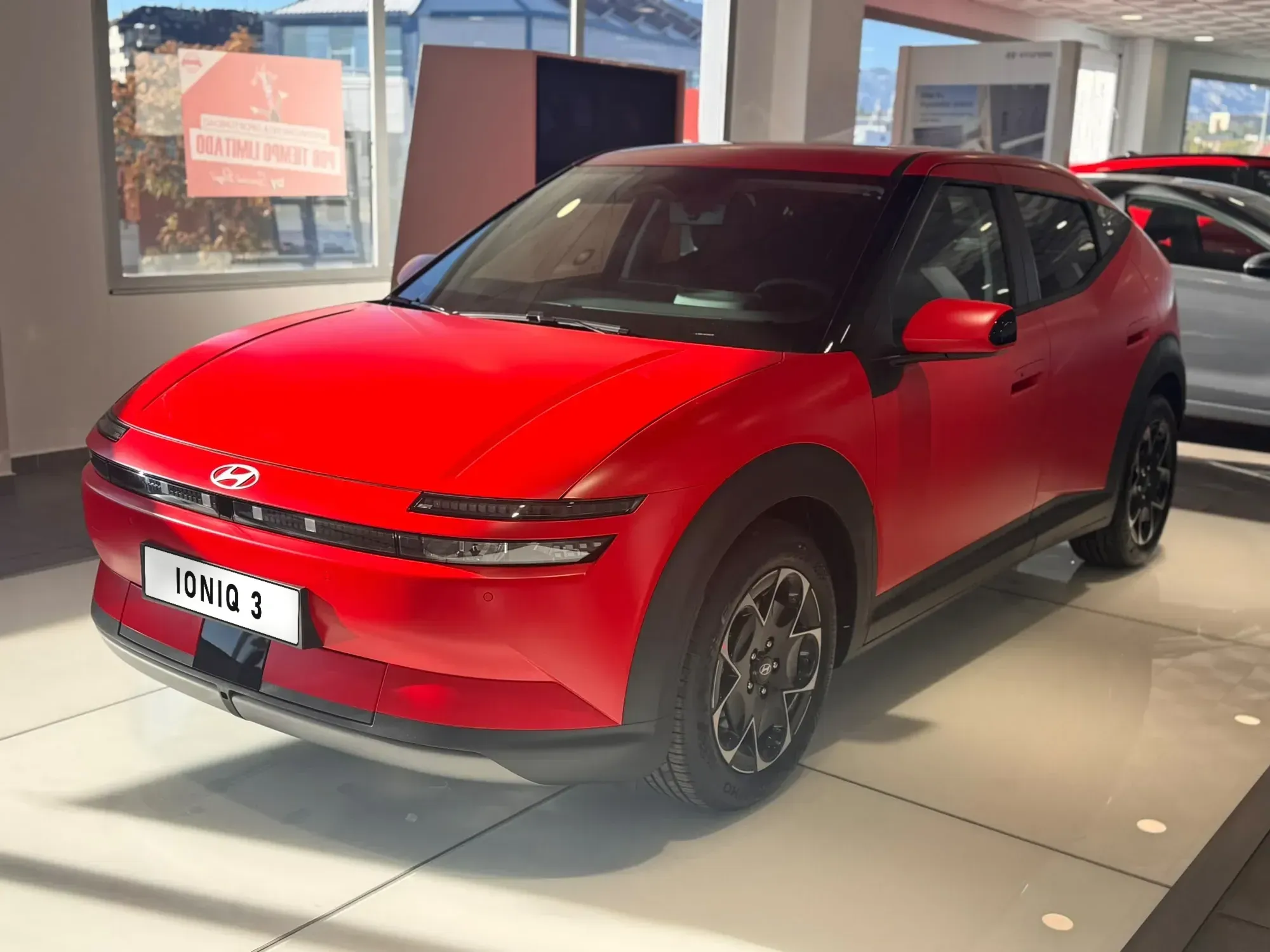 Hyundai IONIQ 3 rojo mate visto de tres cuartos delantero en el concesionario Merodigar Motor