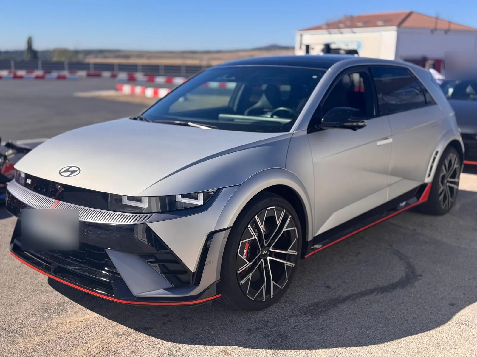 Hyundai IONIQ 5 N gris de tres cuartos delantero con faldón rojo, llantas forjadas de 21 pulgadas y pinzas rojas