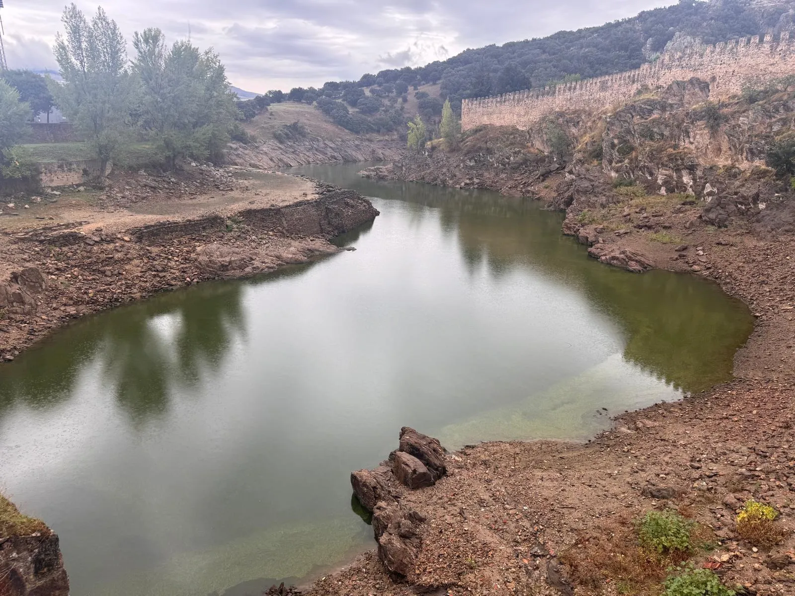El río Lozoya a los pies de la muralla almenada de Buitrago del Lozoya en un día nublado